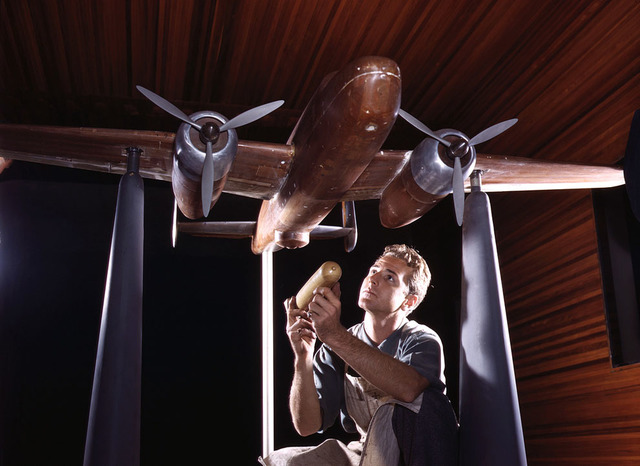 Un modelo a escala experimental del avión B-25 se prepara para las pruebas de túnel de viento en la planta de la North American Aviation, Inc., Inglewood, California. El maquetista sostiene  una reproducción exacta en miniatura de una bomba que llevará  el avión. Foto de octubre de 1942