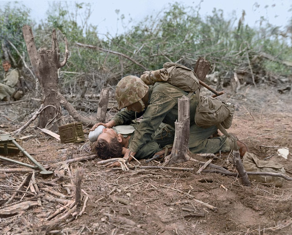 Un marine asiste a un compañero en Iwo Jima, mientras otro, ya sin su casco, observa la dramática imagen